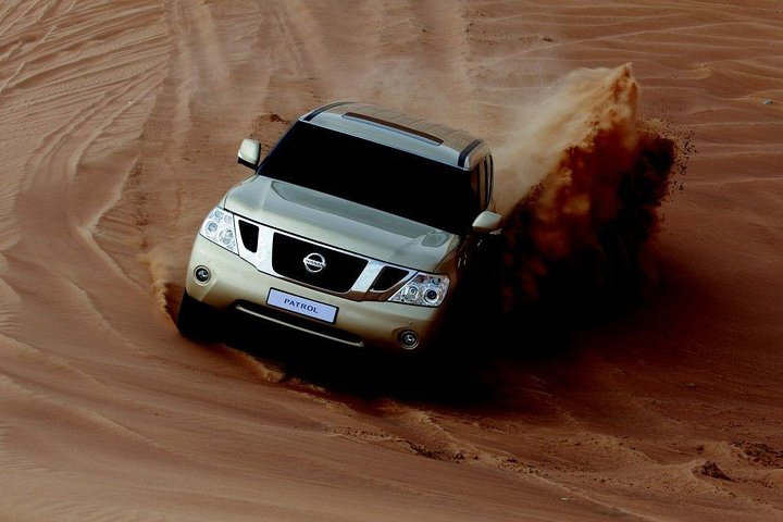 Experience the excitement of riding the dunes in a Nissan Petrol Desert Edition kicking up sand while exploring the stunning desert landscape—an unforgettable adventure awaits every traveler.